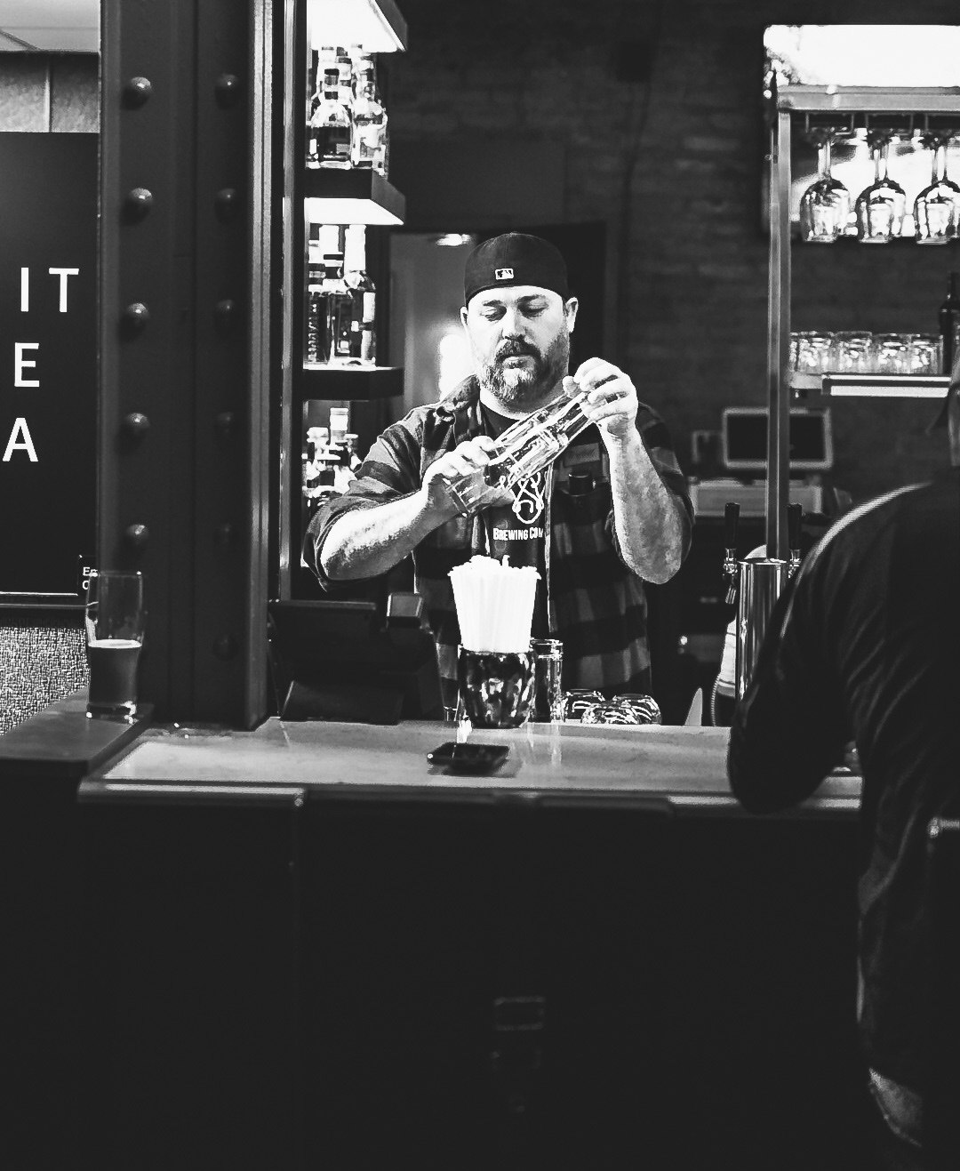 Nick Scott pouring a drink behind the bar at Wild Side Brewing, black and white