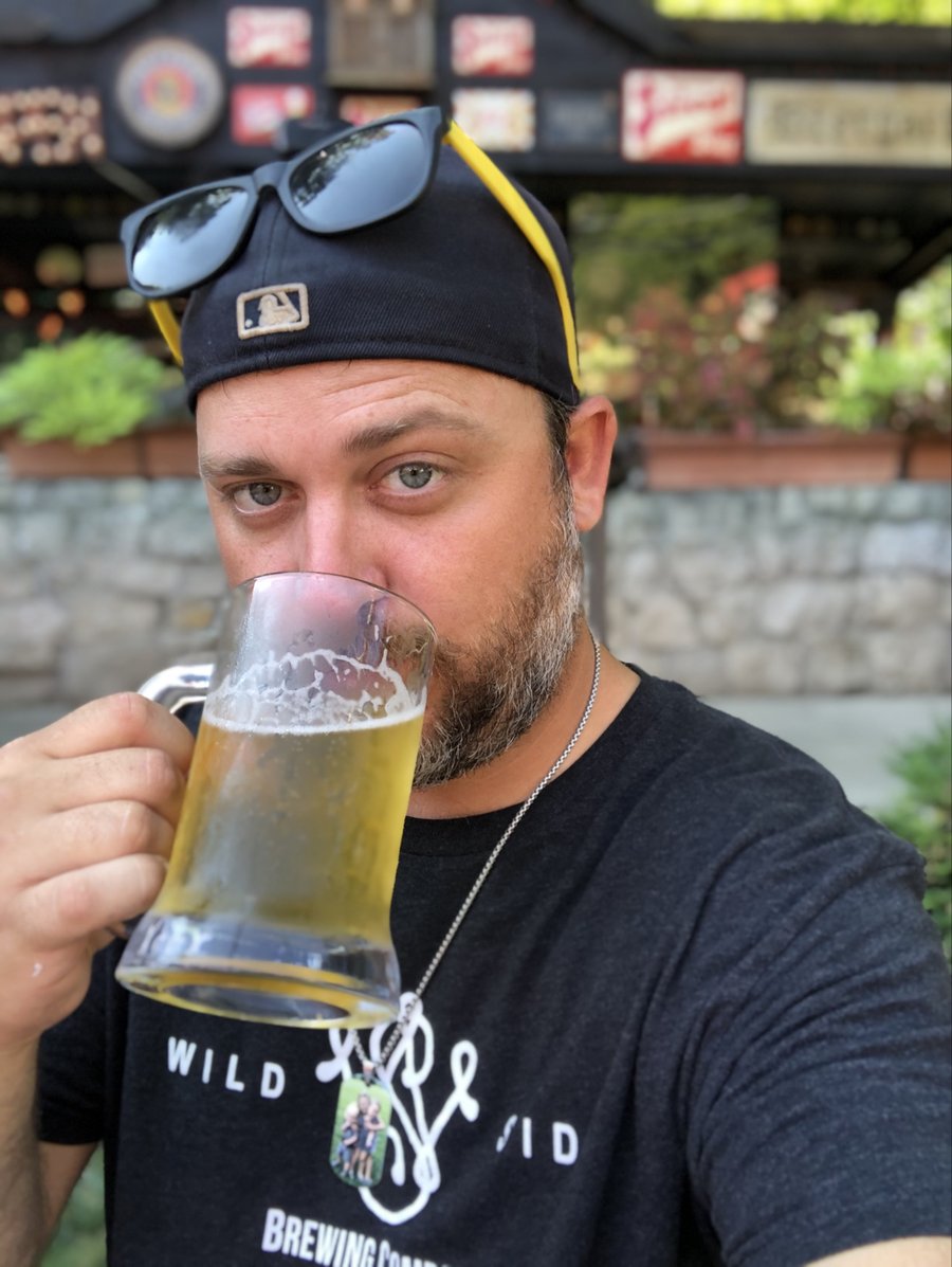 Nick Scott raising a beer, sunglasses tucked into his cap